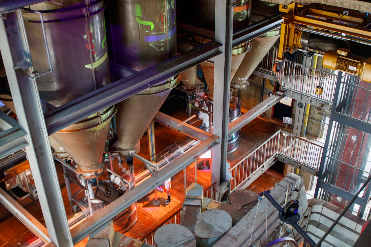 High-angle view of industrial silos inside a factory setting, showcasing complex machinery.